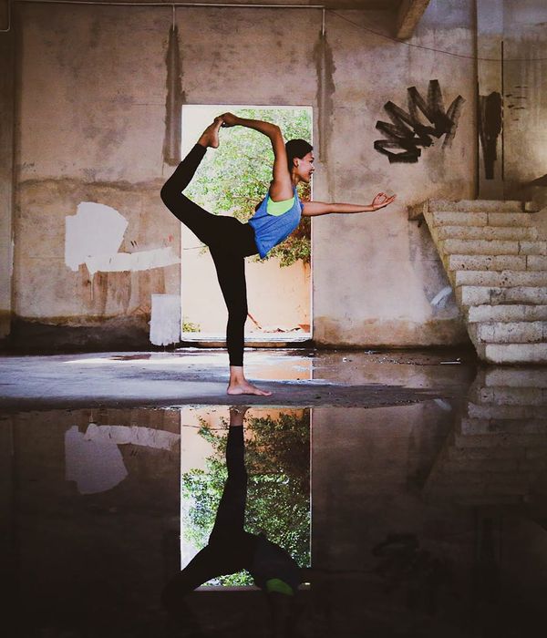 Woman holding a serene yoga pose in a dark room with turquoise light effects.